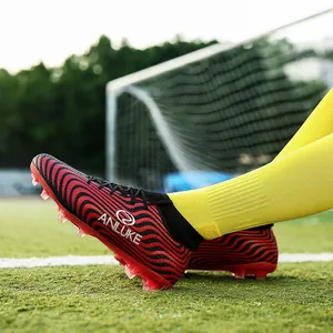 Primer plano de botas de fútbol de caña alta con patrón de ondas rojas y negras en césped