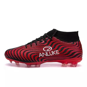Botas de fútbol de caña alta rojas y negras con patrones ondulados y tacos AG resistentes.