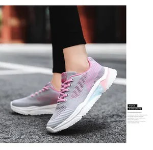 Vista laterale di scarpe da corsa in rete fly-knit traspiranti rosa e grigie