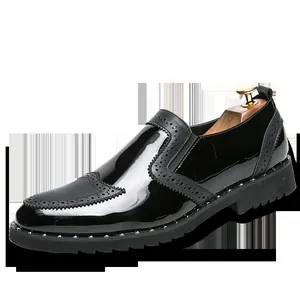 Detailed view of a black patent leather brogue shoe with silver studs on the sole.