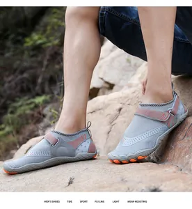 Dettaglio ravvicinato delle scarpe da acqua grigie a cinque dita su terreno roccioso