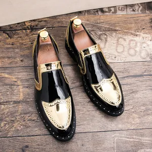 Top-down view of black patent leather brogues with gold metallic wingtip details