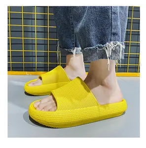 Close-up of bright yellow thick-soled pillow slides worn on feet with denim jeans