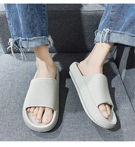 Close-up detail of thick-soled slide sandals worn indoors on a grey fabric surface