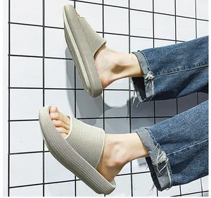 Detailed shot of beige platform slides worn with denim jeans on grid background