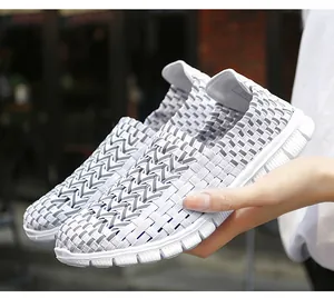 Vue rapprochée de chaussures tressées respirantes gris et blanc tenues à la main