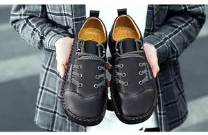 Primer plano de manos sosteniendo zapatos casuales retro negros para hombre