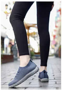 Detailed view of women's blue mesh slip-on sneakers worn on urban stone pavement