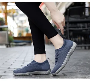Side view of blue flying woven mesh slip-on sports shoes worn with black leggings outdoors