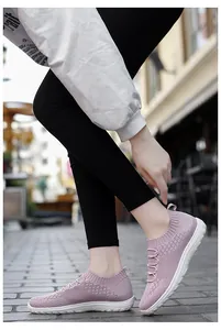 Detail of pink fly-knit mesh slip-on shoes for women in an urban street setting.