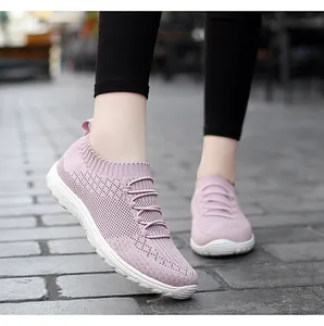 Macro view of stylish pink fly-woven mesh sneakers for women walking on stone pavement