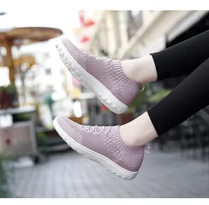 Side view of breathable pink flying woven knit slip-on sneakers for women on the street