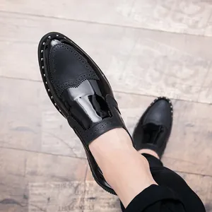 Top down close-up detail of black patent leather brogue shoes with silver rivet studs