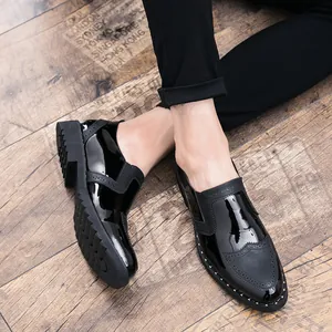 Close-up of black shiny leather brogue shoes with silver studs on wooden floor