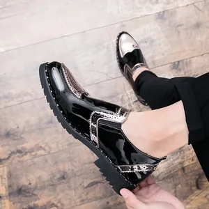 Detailed view of men's black patent leather brogue shoes with silver rivet accents