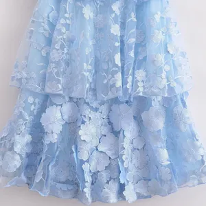 Detailed close-up of light blue 3D floral embroidery and tiered tulle layers on a dress