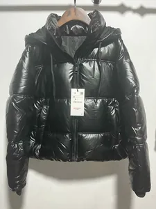 Detailed front view of a stylish black glossy hooded puffer jacket with metallic finish