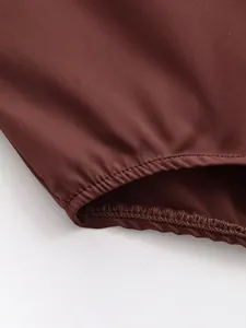 Close-up macro shot of the elasticated hem and zigzag stitching on a brown satin bodysuit
