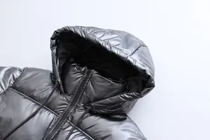 Detail of metallic silver hooded puffer jacket showing shiny fabric texture and zipper.