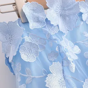 Close-up detail of light blue off-the-shoulder dress with 3D floral embroidery textures