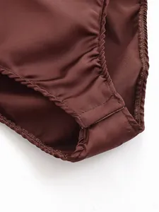 Macro detail view of satin bodysuit crotch showing fabric texture and snap buttons