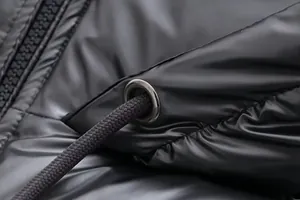 Macro view of metallic shiny fabric and drawstring eyelet on a black puffer jacket