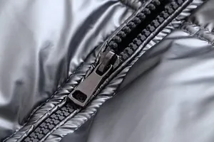 Close-up detail of the durable black zipper on a shiny metallic silver puffer jacket
