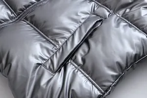 Close-up of metallic silver puffer jacket showing quilted texture and pocket detail