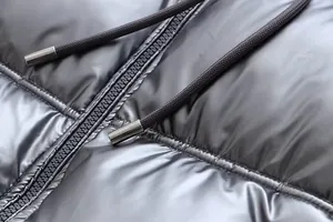 Close-up detail showing the metallic silver fabric and drawstring hardware of a puffer jacket.