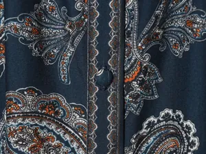 Dettaglio ravvicinato della stampa paisley blu navy e bottone rivestito sul vestito