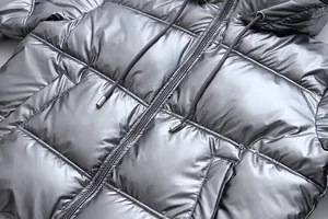 Close-up detail showing the metallic silver shiny fabric of a hooded puffer jacket