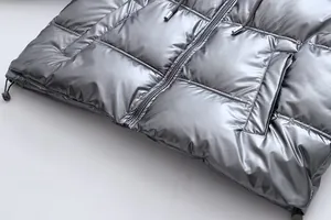 Detailed macro view of a metallic silver shiny hooded puffer jacket showing zipper and hem
