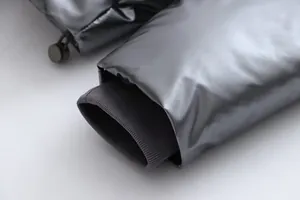Detail showing the metallic shiny fabric and grey ribbed inner cuff of a winter jacket