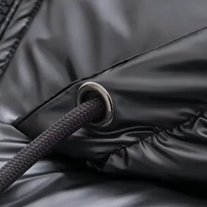 Macro view of the drawstring and metallic eyelet on a shiny black puffer jacket detail.