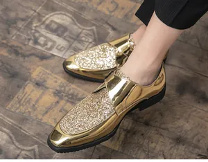 Close-up of men's shiny gold glitter metallic pointed toe dress shoes on floor.