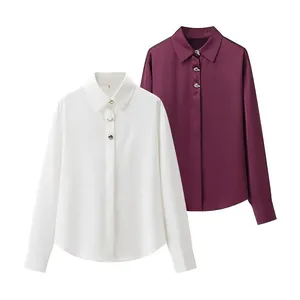 Detail view of white and burgundy satin blouses featuring elegant gold buttons.
