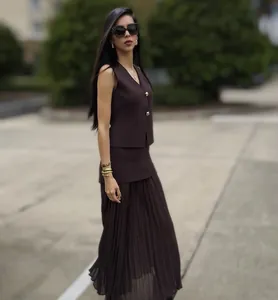 Detailed view of dark brown knitted vest with gold buttons and pleated skirt set