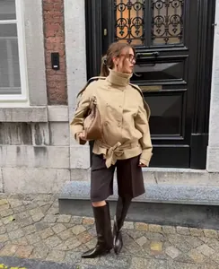 Detailweergave van een stijlvolle kaki trenchcoat met bruine laarzen voor dames