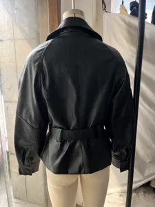 Detailed back view of a black faux leather trench jacket featuring a waist belt