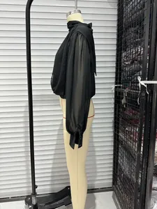 Side view of a black high-neck blouse with bow tie and sheer sleeves on a mannequin.