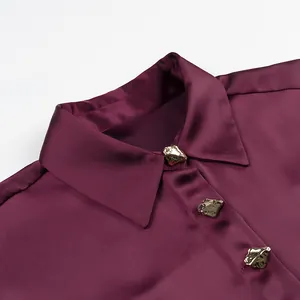Detailed macro view of elegant burgundy satin shirt with artistic gold buttons
