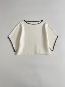 Detail view of white knit top with black contrast blanket stitch embroidery.