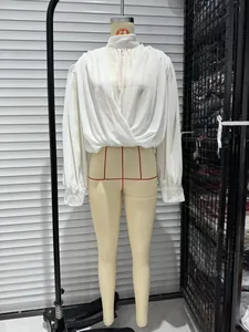 Detailed view of white long-sleeved wrap front blouse with stand collar on mannequin