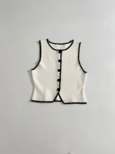 Detailed view of white knit vest featuring contrast black scallop embroidery and buttons