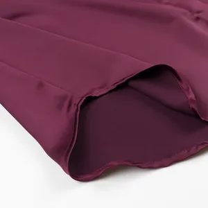 Macro detail view of burgundy satin shirt hem with high-quality stitching finish