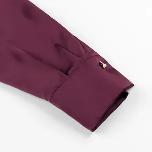 Detail showing the elegant golden button and satin texture of a burgundy silk shirt
