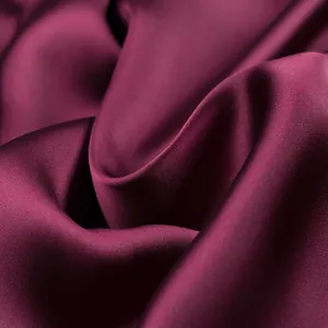 Close-up detail of premium burgundy silk satin fabric showing smooth texture and elegant sheen