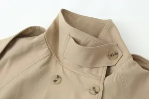 Detailopname van de opstaande kraag en dubbele knopenrij van een kaki trenchcoat voor dames