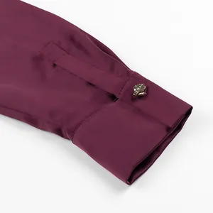 Close-up of elegant burgundy satin shirt cuff with ornate gold-tone textured button detail