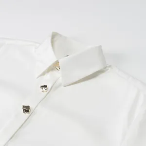 Close-up of white satin blouse collar featuring decorative irregular gold buttons.
